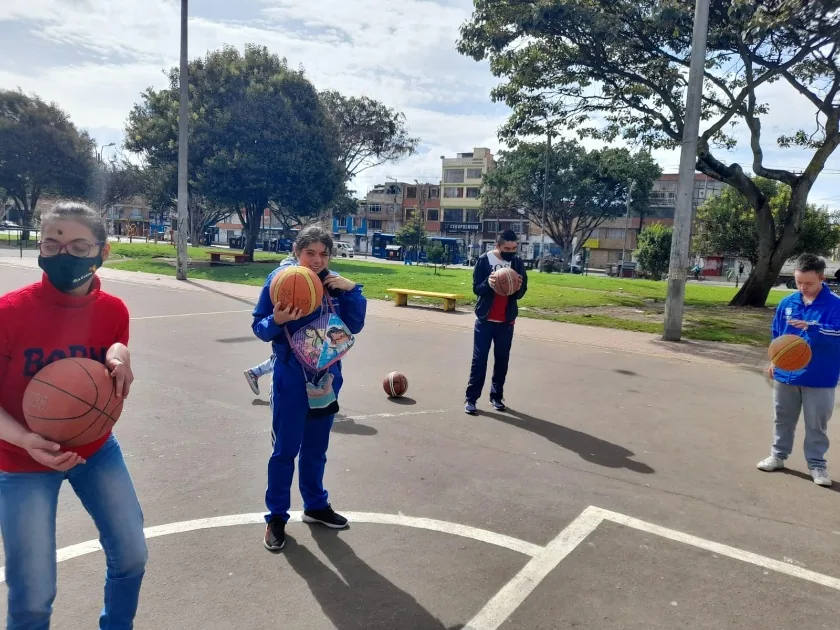 Jóvenes jugando con balones de baloncesto en una cancha de un parque