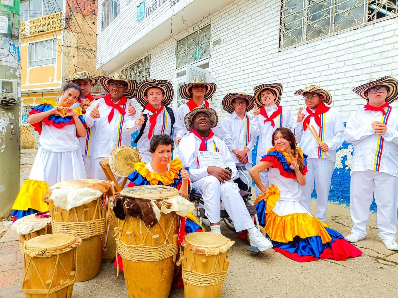 Jóvenes con vestuario blanco, sombrero vueltiao y polleras de colores junto a sus tambores en una calle